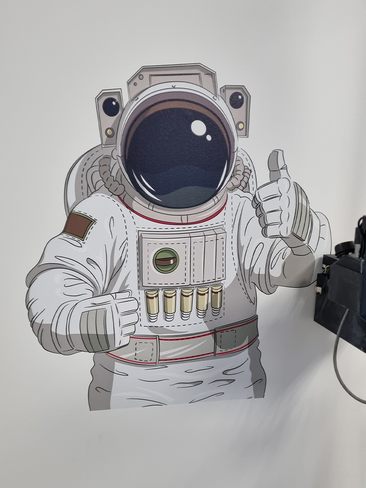 Astronauta pokazujący kciuk w górę wydrukowany na ścianie